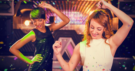 Smiling female friends dancing on dance floor against flying colours