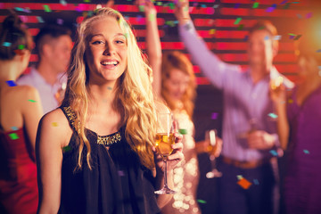 Portrait of young woman holding a glass of champagne against flying colours