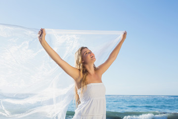 Fototapeta na wymiar Beautiful calm blonde in white sundress on the beach with scarf