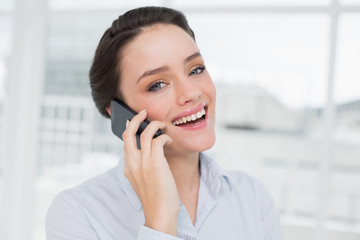 Cheerful elegant young businesswoman using cellphone