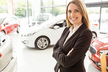 Smiling saleswoman standing with arms crossed