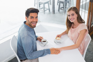 Romantic young couple holding hands at coffee shop