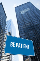 Fototapeta na wymiar The word be patient and blue billboard against low angle view of skyscrapers