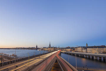 Fototapeta na wymiar Motion blurred light tracks of highway traffic to Old city (Gamla Stan) cityscape pier architecture with historic town houses in Stockholm, Sweden. Creative long time exposure landscape photography