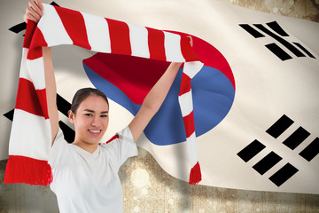 Football fan waving red and white scarf against korea republic flag