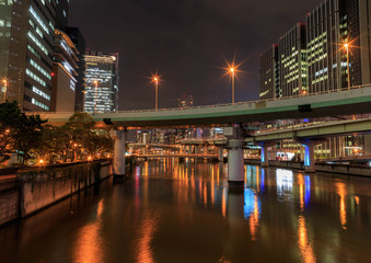 Bridges and highways cross a waterway at night in central Osaka