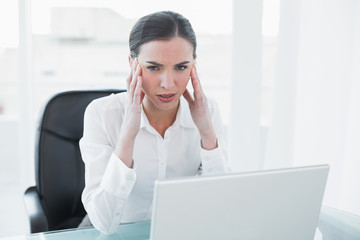 Businesswoman suffering from headache in front of laptop