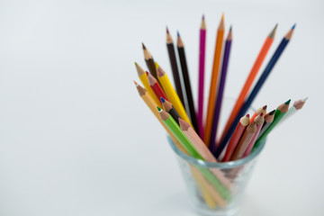 Colored pencils kept in glass on white background