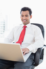 Smiling businessman using laptop at office