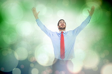 Happy cheering businessman raising his arms against grey abstract light spot design