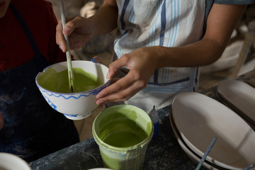 Mid section of female potter and boy painting bowl