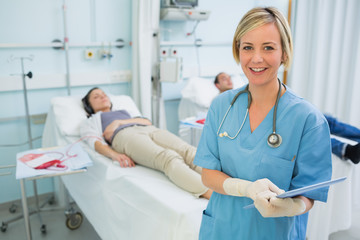 Obraz premium Smiling nurse next to transfused patients