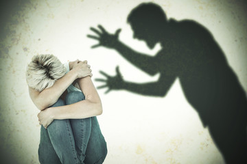 Depressed woman hiding her head  against silhouette of shouting man