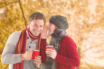 Couple both having warm drinks against tranquil autumn scene in forest