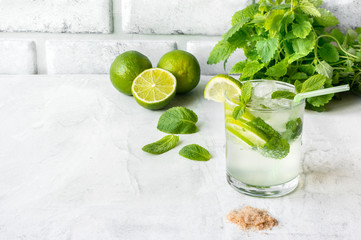 Mojito Cubano (caipirinha cocktail) with lime and mint on a concrete table. Iced summer cold drink. Copy space.