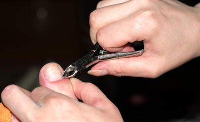 Fototapeta premium Closeup, the girl cares for nails fingers at home. Cleanse the cuticles with nail nippers for manicure