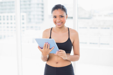 Charming dark haired model in sportswear holding a tablet pc