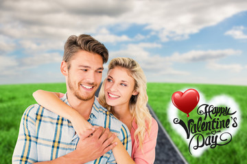 Attractive couple embracing and smiling against road on grass