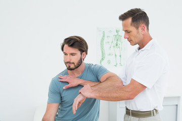Male physiotherapist stretching a young mans hand