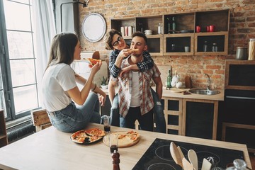 Three friends having fun eating pizza at party