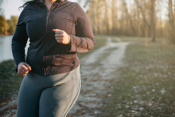 Young overweight woman running in sunrise light