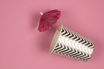 top view paper cup with cocktail umbrella pink background , summer party or summer sale concept