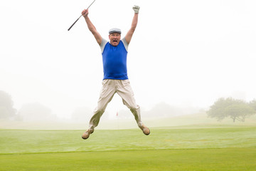 Fototapeta na wymiar Excited golfer jumping up and smiling at camera 
