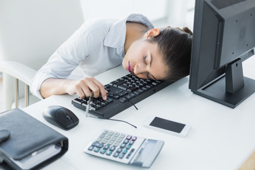 Businesswoman resting head on keyboard in office