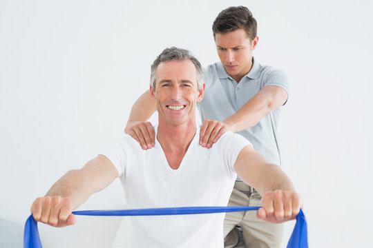Therapist massaging a happy mans shoulder in gym hospital