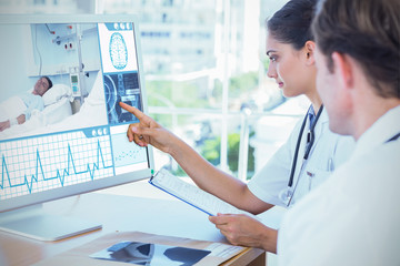 Doctor pointing at the screen of a computer against white background with vignette