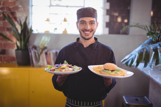 Portrait of smiling young waiter serving fresh food