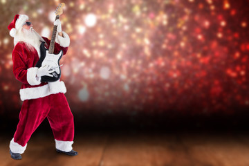 Santa playing electric guitar against shimmering light design over boards