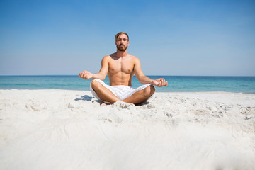 Fototapeta na wymiar Shirtless man meditating at beach