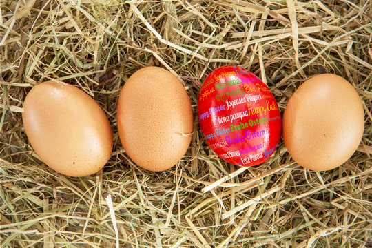 Happy easter in different languages against red egg on straw with plain ones