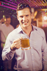 Smiling man holding glass of beer in bar against flying colours