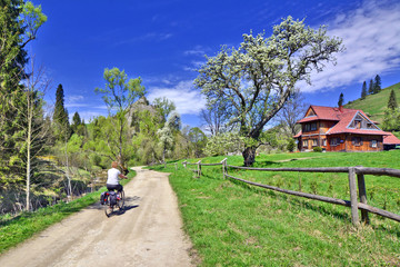 Obraz premium Woman riding a bicycle on a sunny spring day, Biala Woda Reserve, Pieniny mountains, Poland.