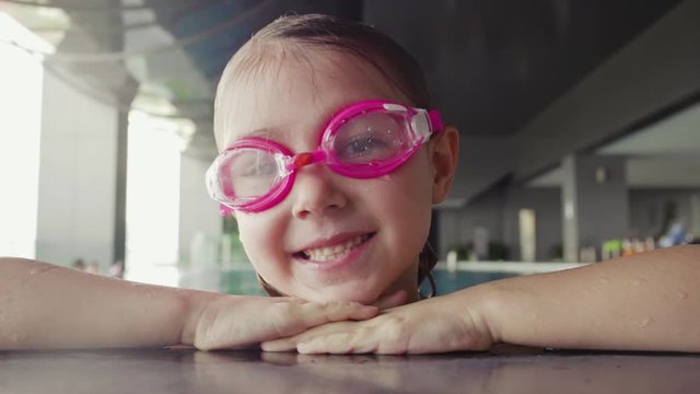 Close-up of young girl in goggles swimming in pool