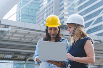 attractive woman architecture and woman engineer together working at outdoor with laptop on working site.