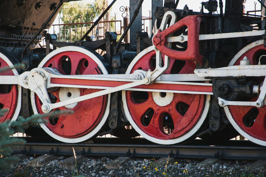 large steel wheels of old steam locomotive, red with white outline