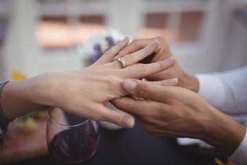 Man putting engagement ring on woman hand