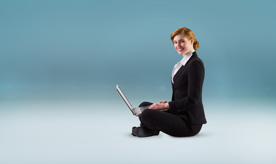 Redhead businesswoman using her laptop against blue vignette background
