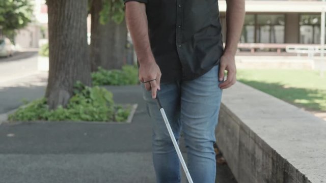 blindness, disability - young blind man walks helped by the stick