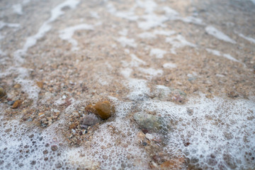 Fototapeta na wymiar Sea waves on the beach with full of stone