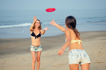 two beautiful women playing flying disk on the beach
