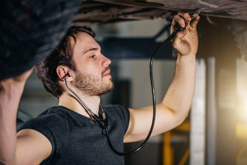 mechanic listen engine with stethoscope in repair garage