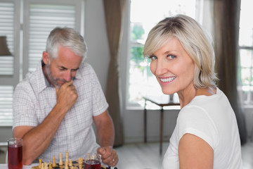 Happy mature couple playing chess at home