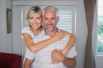 Smiling woman embracing mature man at home