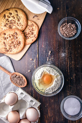 Chocolate cookies on wooden table with flour eggs and ingredients
