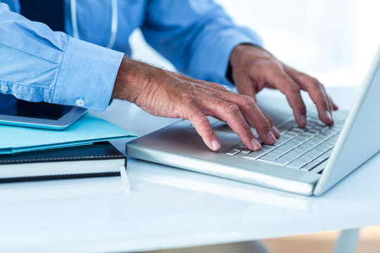 Cropped image of businessman using laptop in office