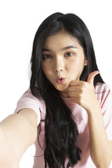 Asian girl taking selfie photo while makinging funny face and took her thumb up.